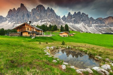Yüksek tepeleri, ahşap kireçleri ve dağ gölü olan inanılmaz bir dağ manzarası. Ünlü Geisler - Gün batımında arka planda Odle zirveleri, Alto Adige, Dolomitler, İtalya, Avrupa