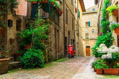 Muhteşem geleneksel bir şekilde dekore edilmiş sokak çiçekli ve rustik evler, eski scooter ayakta tipik İtalyan street, Pienza, Toskana, Avrupa'nın moda