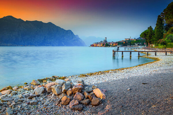 Fantastic recreation place, Malcesine touristic resort, amazing gravel beach and stunning sunset, Garda lake, Veneto region, Italy, Europe