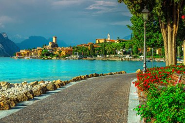 Görkemli Malcesine turistik dinlenme tesisi, renkli çiçekler ve arka plan, Garda Gölü, Veneto bölgesi, İtalya, Avrupa'nın Akdeniz binalar ile döşeli patika