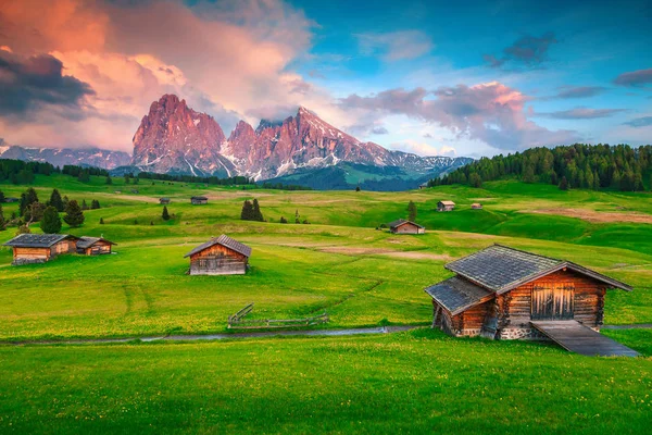 Alpine green fields and wooden chalets at sunset, Dolomites, Italy — Stock Photo, Image