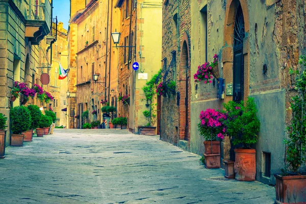 Bakstenen en stenen huizen versierd met kleurrijke bloemen, Pienza, Italië — Stockfoto
