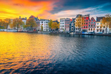 Amsterdam, Hollanda 'da sonbahar şehir manzarası ve ev tekneleri ile su kanalı