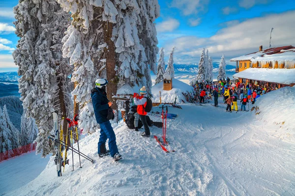 Estância de esqui com esquiadores e casa de madeira, Poiana Brasov, Roménia — Fotografia de Stock