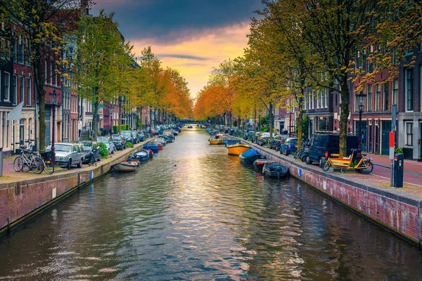 Smal waterkanaal met boten bij zonsondergang in Amsterdam, Nederland — Stockfoto