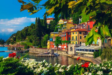 Göl kıyısındaki çiçekli bahçe ve renkli binaları olan güzel bir manzara Como Gölü, Varenna, İtalya, Avrupa
