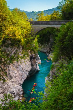 Güzel rafting ve kano yerleri. Kobarid, Triglav Ulusal Parkı, Slovenya, Avrupa yakınlarındaki eski taş köprünün altındaki zümrüt rengi Soca nehrinde kürek çeken sporcu sporcular
