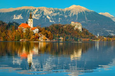 Bled Gölü ile sonbahar manzarası. Gölün kıyısındaki şirin hac kilisesi ve arka plandaki uçurumlardaki muhteşem kale, Bled, Slovenya, Avrupa