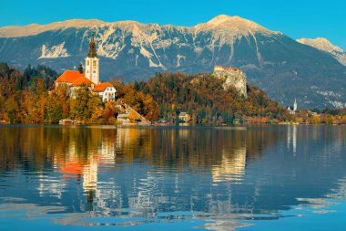Autumn landscape with lake Bled. Cute Pilgrimage church on the shore of lake and spectacular fortress on the cliffs in background, Bled, Slovenia, Europe clipart