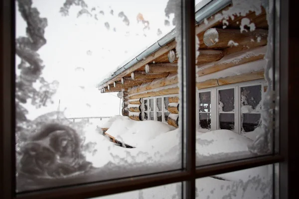 View of the snow-covered house through the window.