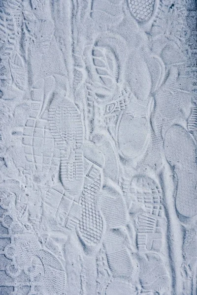 footprints on the white sand on the ground on the street