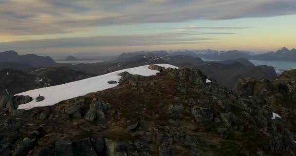 Antenne - pannen rond jonge man wandelen naar de top van de berg. permanent overwinning op de top van de berg bij zonsondergang — Stockvideo