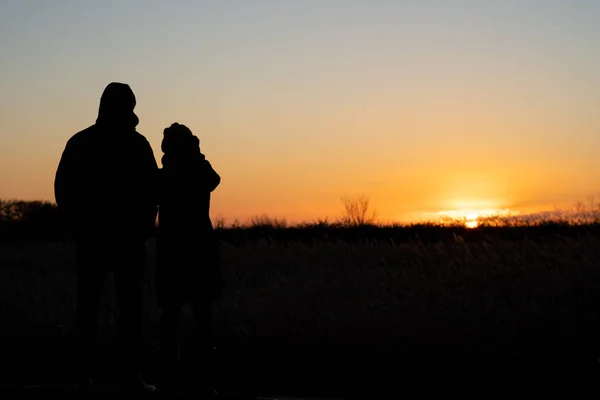 Silhouette eines Paares, das steht und den Sonnenuntergang beobachtet — Stockfoto
