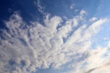 Mavi bir gökyüzünde güneş ışığında beyaz ve gri kümülüs bulutları ile güzel karışık bulut oluşumları