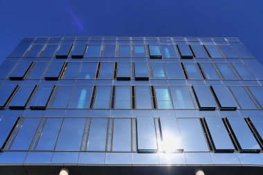 Almanya 'da Kiel' de bulunan pencerelere cam ve güneş ışığı yansıtan modern ofis cepheleri.