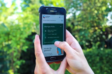 Almanya 'nın kuzeyinde Schleswig-Holstein - 19 Haziran 2020: Yeni Alman Corona virüs uygulamasını gösteren bir kadın eli tarafından tutulan akıllı telefon