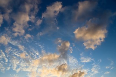 Güneş doğarken ve batarken mavi gökyüzünde turuncu ve sarı bulutlardan oluşan güzel bir manzara.