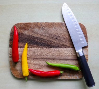 Ahşap kesme tahtasındaki kırmızı biber ve bıçağın izole edilmiş arka planda üst ve perspektif görüntüsü