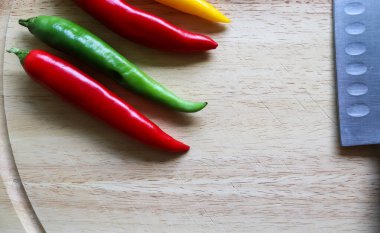 Ahşap kesme tahtasındaki kırmızı biber ve bıçağın izole edilmiş arka planda üst ve perspektif görüntüsü