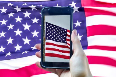 Amerikan bayrağı büyük bir Amerikan bayrağının önünde akıllı telefon ekranında