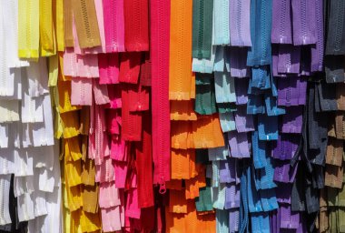 Kumaş pazarında bulunan farklı renklerde fermuar örneklerinin detaylı yakın plan görüntüsü.