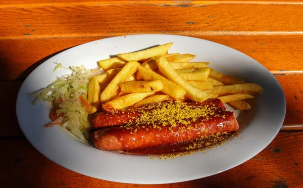 Tradycyjny Niemiecki Currywurst Podawany Chipsami Białym Talerzu Pomarańczowy Drewniany Stół — Zdjęcie stockowe