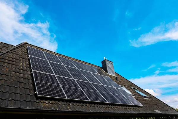 Fotovoltaik paneller, parlak mavi gökyüzü altında sürdürülebilir enerji üretimi için güneş enerjisini kullanan bir çatıya kurulur.