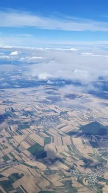 Aerial view from an airplane window flying over a rural landscape. The patchwork of agricultural fields and small villages passes below