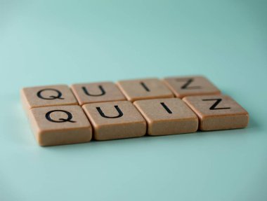 Tahta küplerin kelime sınavı bir turkuaz yüzey üzerinde yatıyor, bilginin test edilme konseptini temsil ediyor.