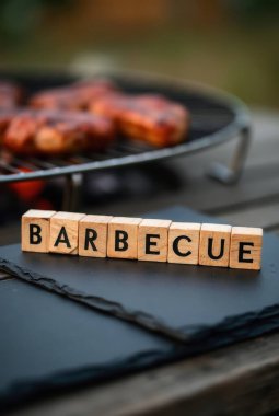 Mangalda ızgara yapan sosisler ve ön planda mangal yapan ahşap küpler.