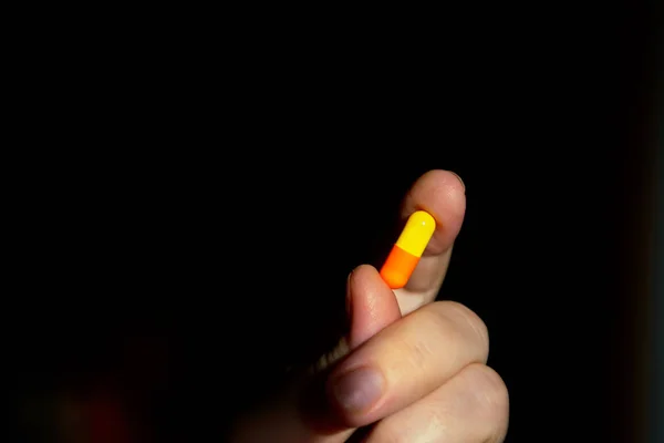 yellow-red pill in female fingers