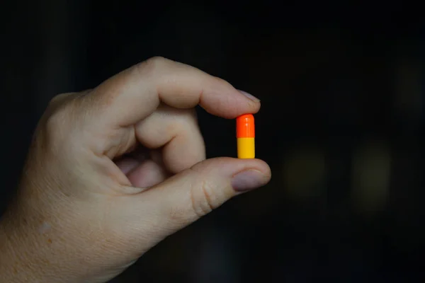yellow-red pill in female fingers
