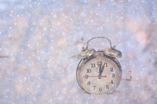 old alarm clock stands in the snow