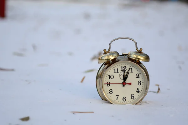 old alarm clock stands in the snow