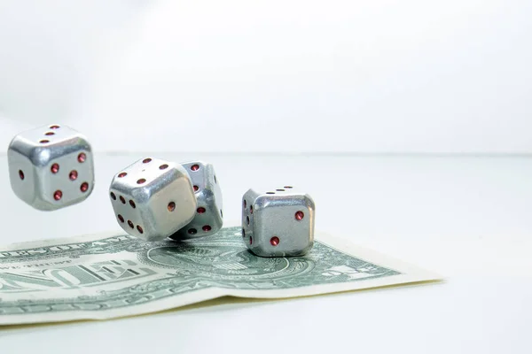 Metallic dices rolled on a one dollar note. Dice photographed in motion. Concept - catch luck