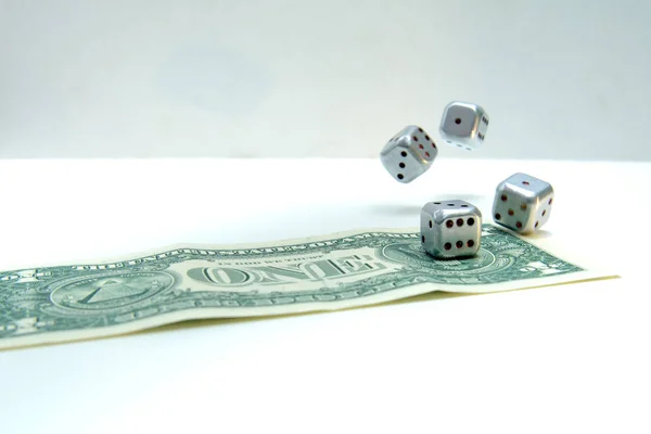 Metallic dices rolled on a one dollar note. Dice photographed in motion. Concept - catch luck