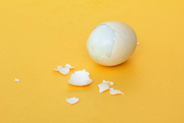 kırık bir kabuk ile sarı bir arka plan üzerinde haşlanmış tavuk yumurtası