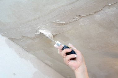 Erkek el mala tutar, tavandaki çatlakları kapatarak.