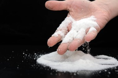 Genç bir adamın avucunun üzerine bir tutam tuz döküyor. Siyah arka plan daki resim. Konsept - sağlık
