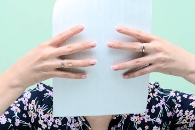 Kız yüzünü beyaz bir kağıtla kapladı. Çarşafın üzerinde manikürlü kadın parmakları var. Kavram - ilişkilerde gizlilik