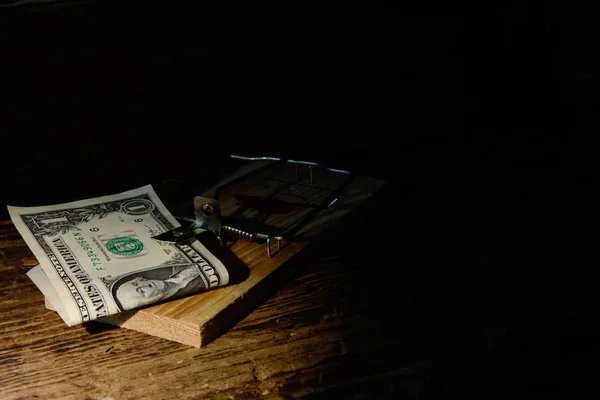 In the wooden mouse trap there is a ten euro bill against a dark background. Concept - risky financial transactions, fraud, risky investments. \