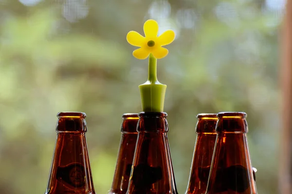 neck dark bottles and a rubber stopper in the form of a flower on a blurred green background. The concept is a natural natural wine. Fight against counterfeit