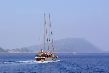 Açık güneşli bir günde dağların arka planında Akdeniz'de ahşap yat. Kavram - denizde tatil. Deniz turizmi. Akdeniz Gezisi