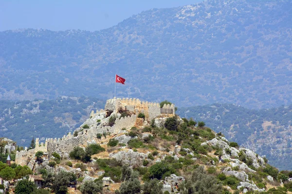 Ancient fortress on a hill. Surrounded by ramparts. Above the fortress is the Turkish flag. Concept - Ancient Cities on the Mediterranean