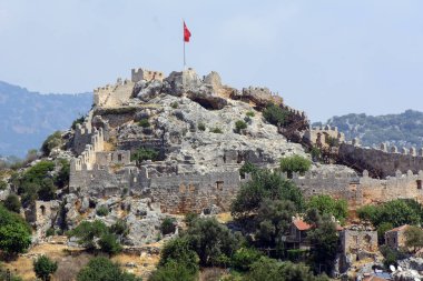 Bir tepede antik kale. Surlarla çevrili. Kalenin üstünde Türk bayrağı var. Konsept - Akdeniz'deki Antik Kentler