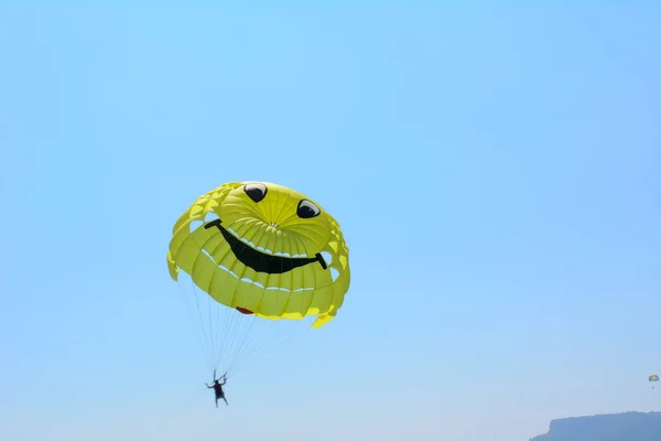 微笑む太陽の形をした黄色いパラシュートが空に浮かんでいる コンセプト エクストリームバケーション — ストック写真