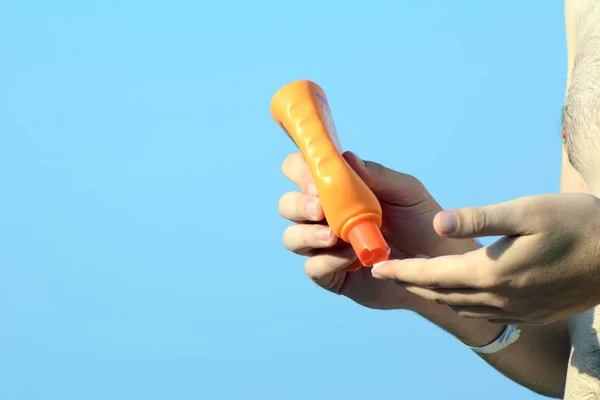 In male hands a tube with sunblock. A man squeezes cream on his finger. Concept - Safe Tan