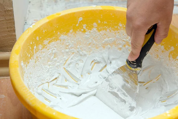 Plastik bir kapta, çalışan bir spatula terbiye karışımı ile müdahale - alçı. Konsept - ev onarımı