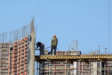 Mavi gökyüzüne karşı kurulumcular metal yapılar topluyor. Kavram - yükseklerde çalışmak, metal yapıların toplanması