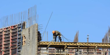 Mavi gökyüzüne karşı kurulumcular metal yapılar topluyor. Kavram - yükseklerde çalışmak, metal yapıların toplanması